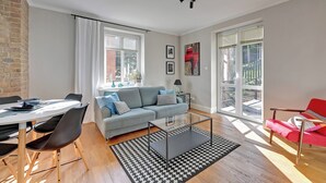 Una sala moderna con un sofá, una mesa de comedor y una silla roja.