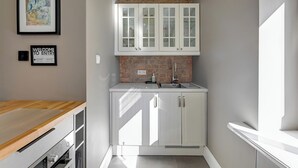 Una cocina con armarios blancos, salpicadero de ladrillo y encimera de madera.