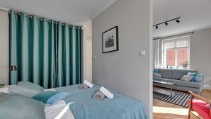 Un dormitorio con cama, sofá y ventana con cortinas.