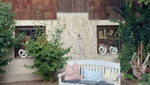 A rustic wooden building with a sloped roof, a bench in front, and a deer head decoration.