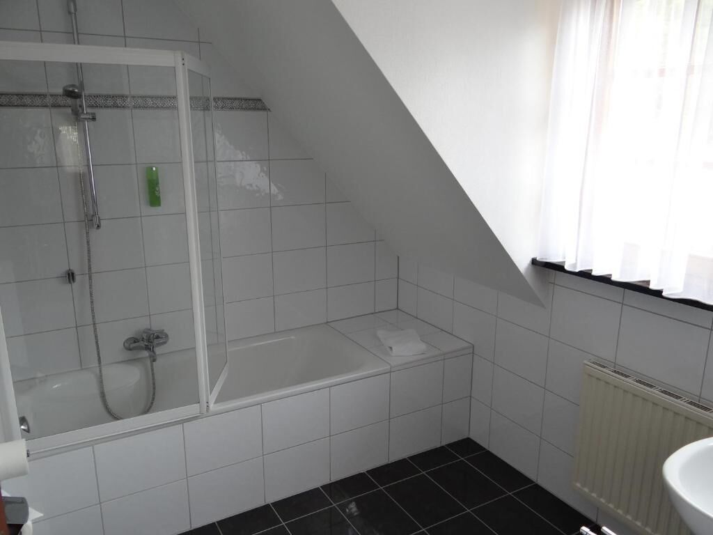 Un baño con ducha, bañera y ventana con cortinas.