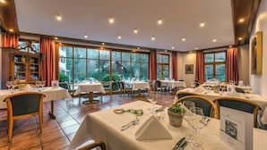 A restaurant with multiple tables, chairs, and a view of the outdoors through large windows.