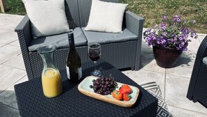 An outdoor seating area with a wicker sofa, a table with a bottle, a glass of wine, a pitcher of orange juice, and a plate of grapes and strawberries. - Tumbledown Croft.
Beautiful cottage in Aberdeenshire countryside near Cruden Bay (Hatton)