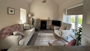 A living room with a fireplace, sofa, armchair, and a television. - Tumbledown Croft.
Beautiful cottage in Aberdeenshire countryside near Cruden Bay (Hatton)