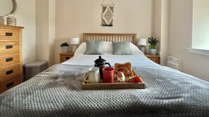 A neatly made bed with a tray of breakfast items, a bedside table with a lamp, and a wall-mounted decorative piece. - Tumbledown Croft.
Beautiful cottage in Aberdeenshire countryside near Cruden Bay (Hatton)