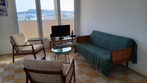 En stue med sofa, to lænestole, sofabord og fjernsyn.
