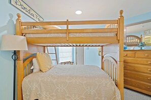 Una cama individual con cabecera, una lámpara de noche y un aparador con cajones.