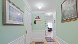 A hallway with framed pictures, a coat rack, and a rug.