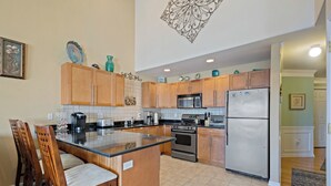 A kitchen with wooden cabinets, a central island, stainless steel appliances, and a decorative ceiling piece.