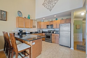 A kitchen with wooden cabinets, a central island, stainless steel appliances, and a decorative ceiling piece.