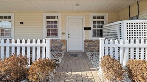 A house with a white picket fence, a brick pathway, and a white door.