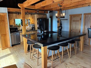 A modern kitchen with wooden cabinetry, a black countertop, and bar stools.