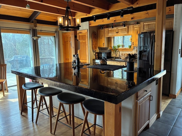 A kitchen with a large island, wooden cabinets, and bar stools.
