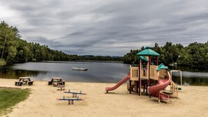 Un'area giochi con scivolo e altalene vicino a un lago.
