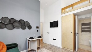 Ein modernes Zimmer mit Bett, Schreibtisch, Fernseher und Kleiderschrank.