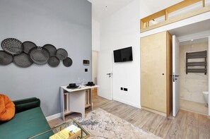 A modern room with a bed, a desk, a TV, and a wardrobe. - Stylish High-Spec Apartment Close to Camden (London)