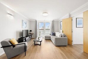 Ein modernes Wohnzimmer mit einer Couch, Sesseln, einem Couchtisch, einem Fernseher und Kunstwerken an den Wänden.