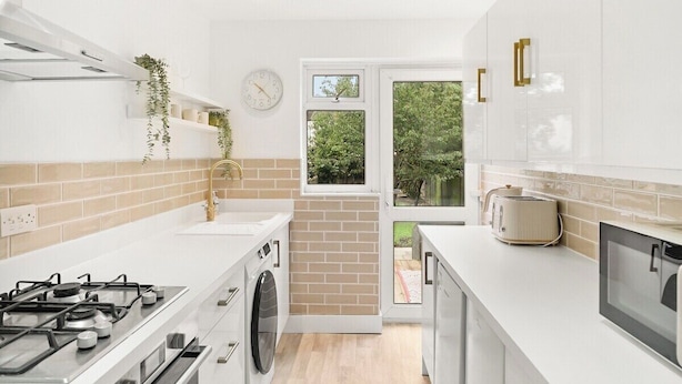 Una cucina moderna con piano cottura a gas, lavatrice e vista sul verde attraverso una finestra.