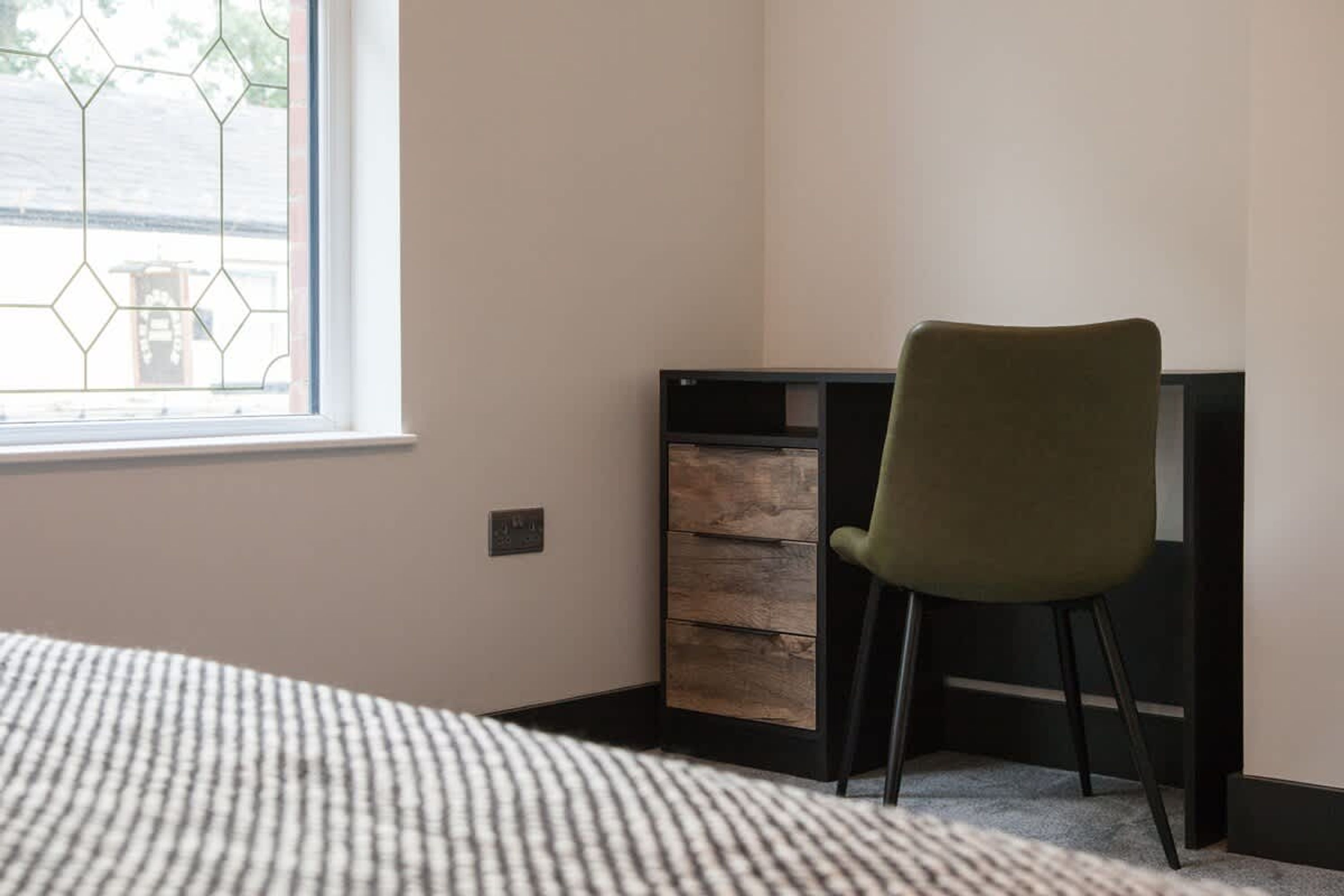 A bedroom with a bed, a desk, and a chair.