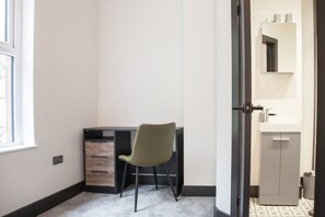 Ein Zimmer mit Schreibtisch, Stuhl und einer Tür zu einem Badezimmer.