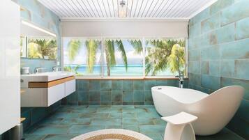 A modern bathroom with a view of the ocean, a freestanding bathtub, and a large mirror.
