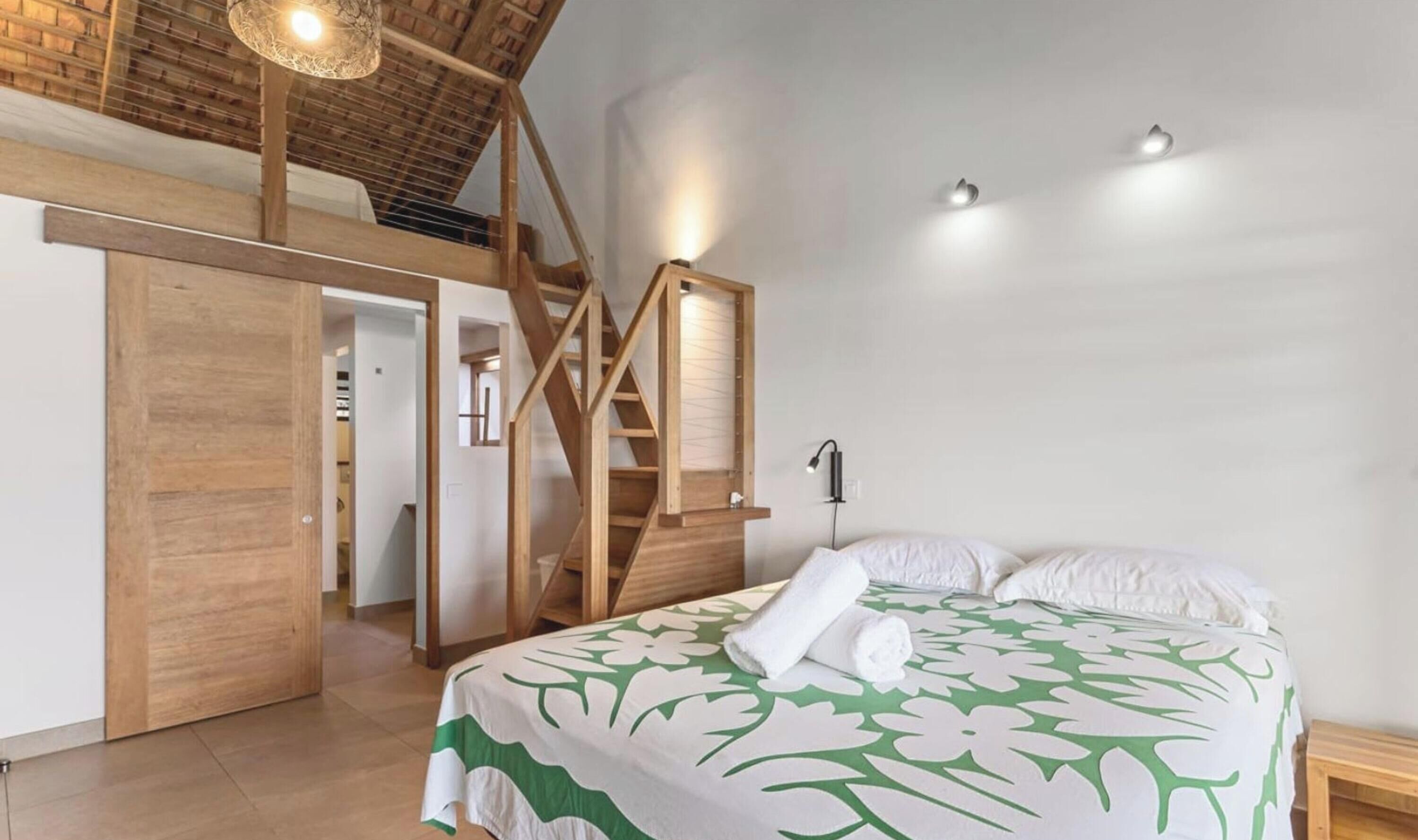 A bedroom with a bed, a wooden staircase, and a closet.