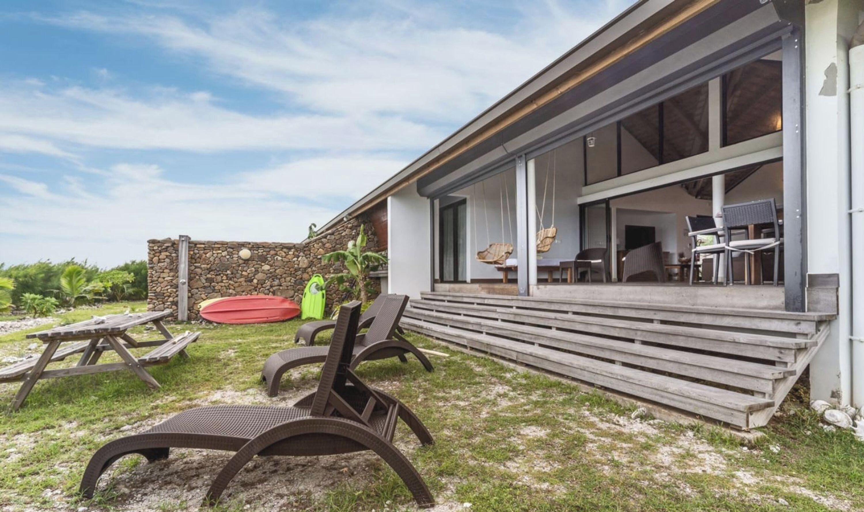 Een modern huis met een overdekte patio, buitenmeubels en een stenen muur.