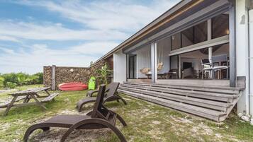 Een modern huis met een overdekte patio, buitenmeubels en een stenen muur.