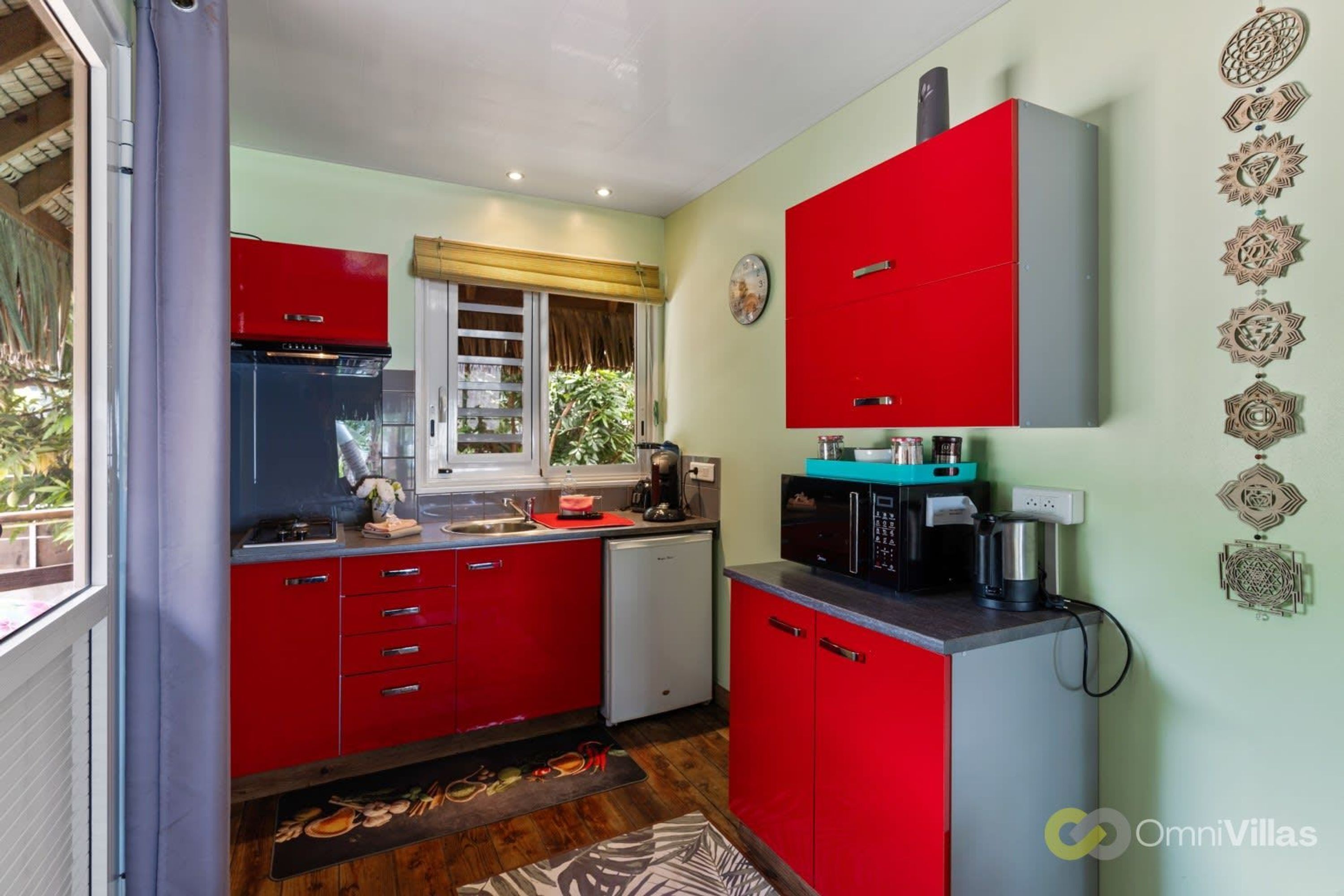A compact kitchen with red cabinets, a coffee maker, and a microwave.