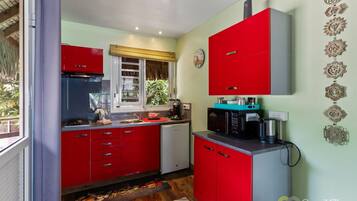 A compact kitchen with red cabinets, a coffee maker, and a microwave.