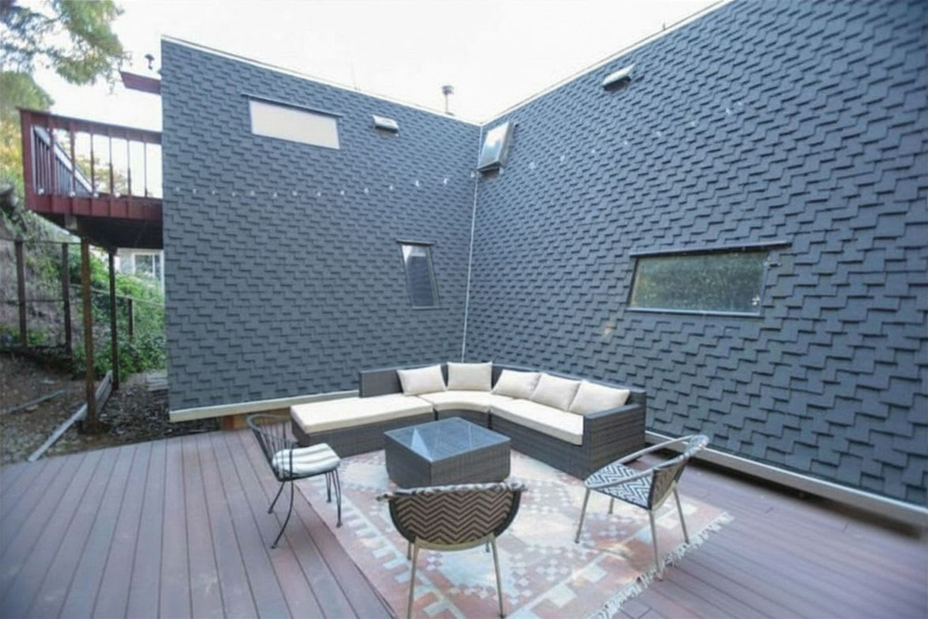 Un patio exterior moderno con un sofá curvo, dos sillones y una mesa de centro.
