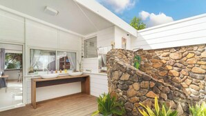 A modern kitchen with a stone wall, wooden deck, and a large window. - Seaside Serenity 2BR Oasis on Enchanting Moorea (Moorea-Maiao)