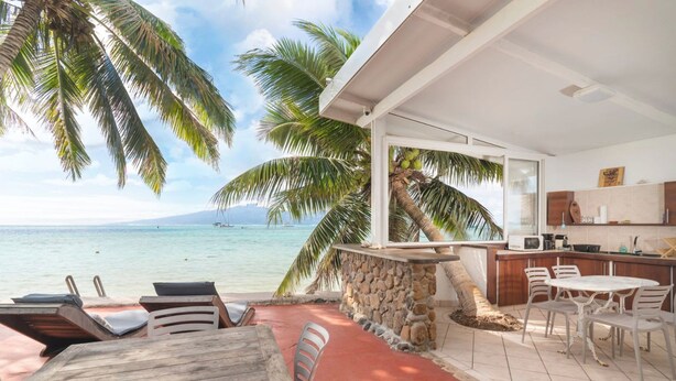 A beachfront property with a stone wall, a bar area, and a dining setup overlooking the ocean. - Seaside Serenity 2BR Oasis on Enchanting Moorea (Moorea-Maiao)