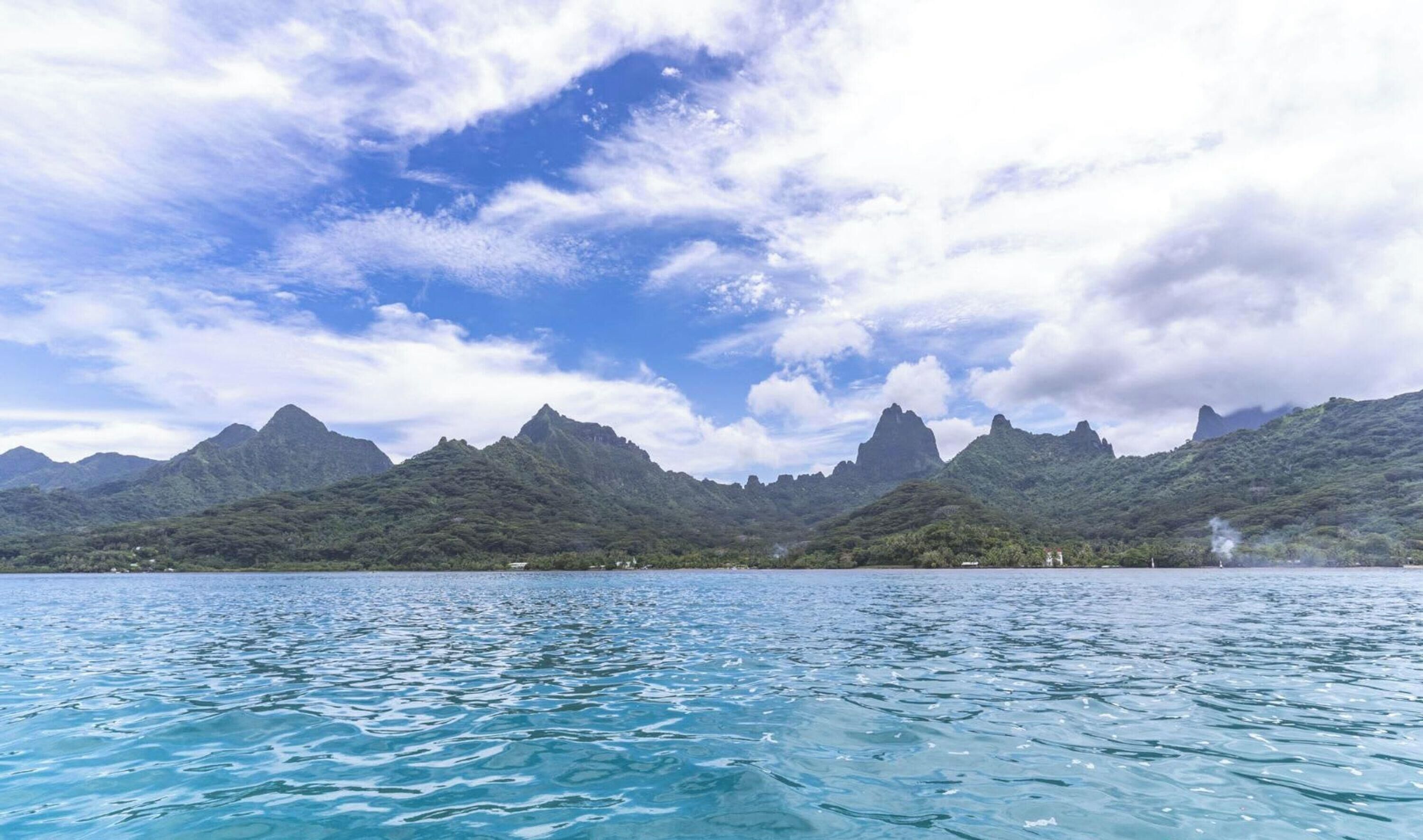 Eine Berglandschaft mit klarem, blauem Wasser im Vordergrund.
