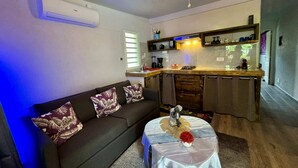 A living room with a sofa, a ceiling fan, and a small table with a decorative item. - Chic Beachside Retreat (Moorea-Maiao)