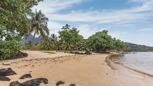 A beach with sand, rocks, and palm trees. - Seaside Paradise Retreat - 3BR House in Moorea (Moorea-Maiao)