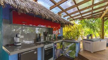 An outdoor kitchen with a gas stove, a coffee maker, and a refrigerator.