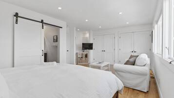 A bedroom with a large bed, a chair, a TV, and a wardrobe.
