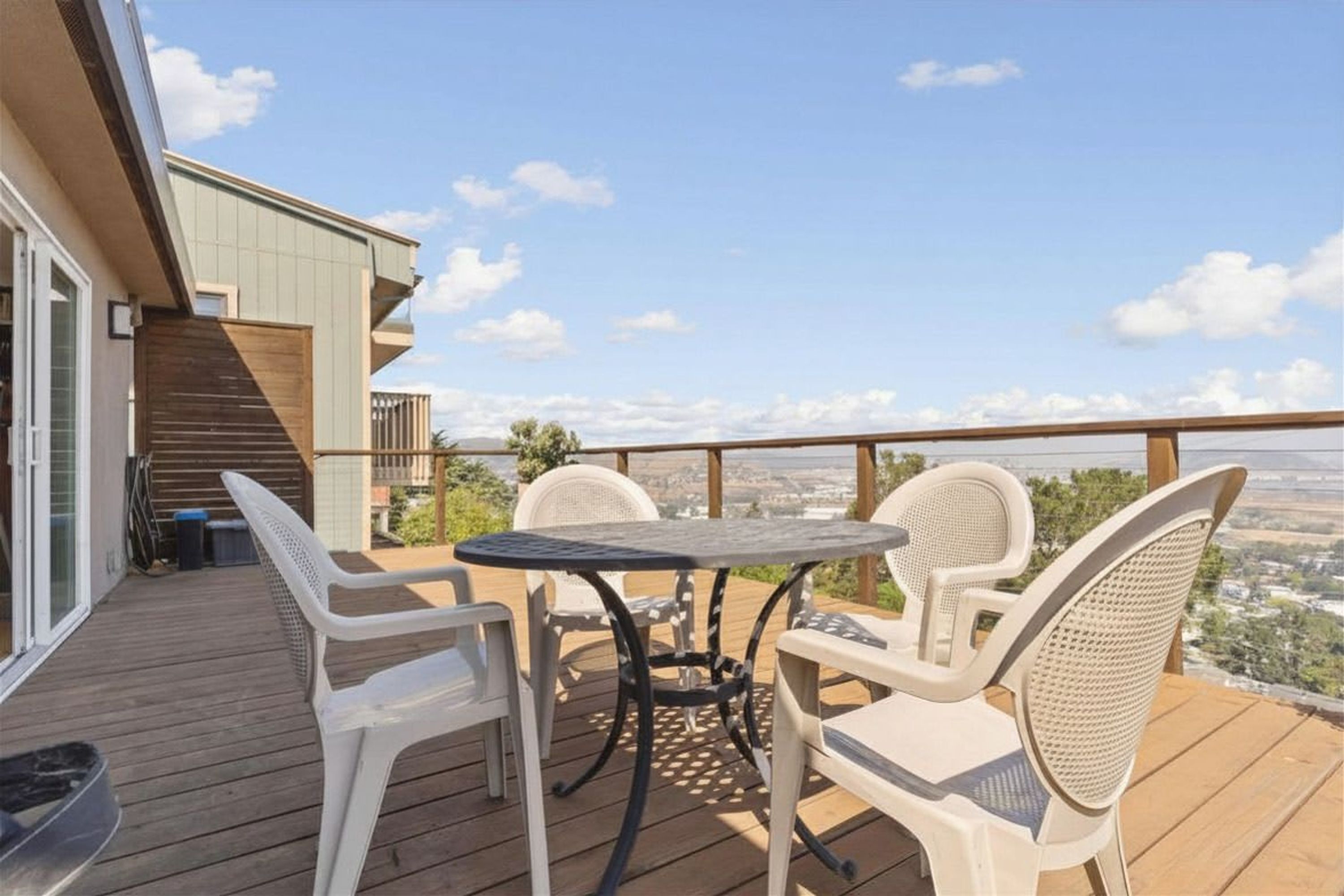 A deck with a table and chairs, overlooking a cityscape.