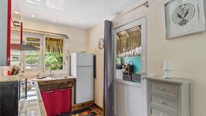 A compact kitchen with a refrigerator, sink, and a window with curtains. - Beachfront Bungalows With Sunset Views in Haapiti (Moorea-Maiao)