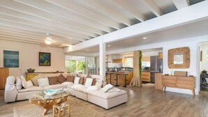 Amplia sala de estar con un sofá modular grande, una mesa de centro de vidrio y piso de madera.