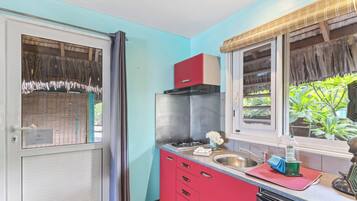 A compact kitchen with a gas stove, a sink, and a red cabinet.