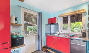 Una cocina pequeña con un refrigerador, una cafetera y un lavamanos.