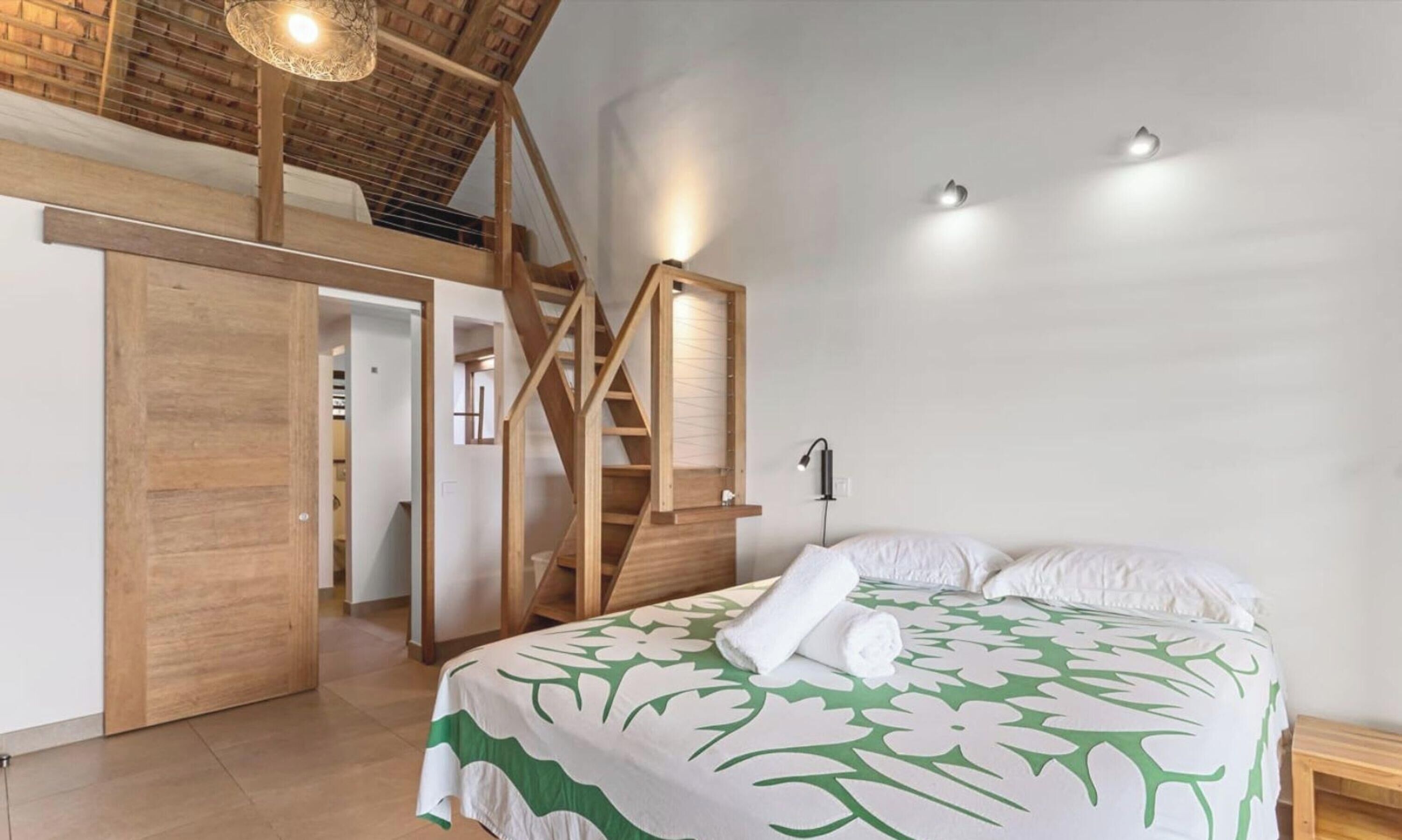 A bedroom with a bed, a wooden staircase, and a closet.