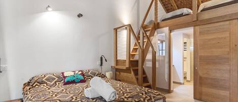 Une chambre avec un lit, un escalier en bois et un espace aménagé en mezzanine.