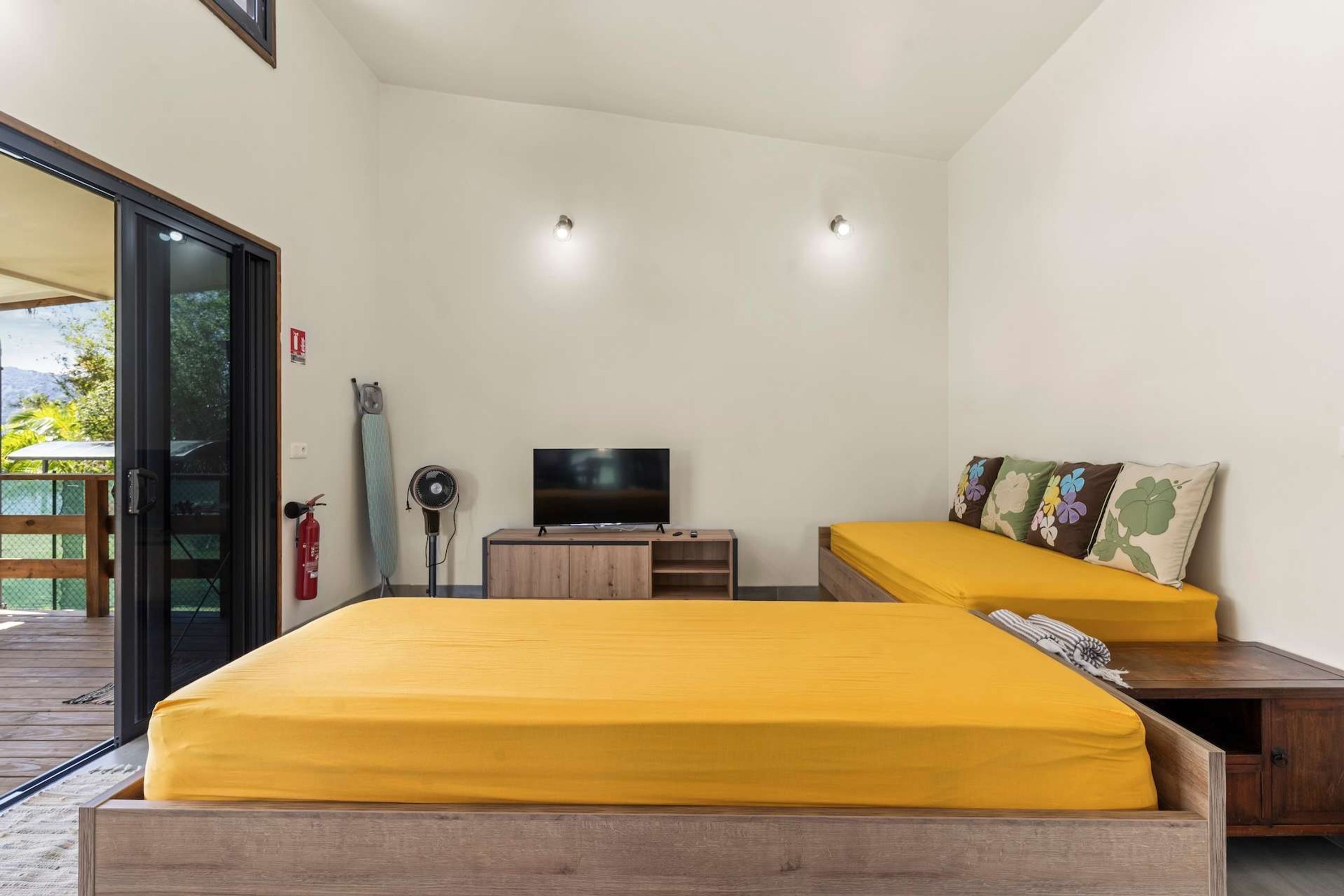 A room with two beds, a TV, a fire extinguisher, and a wooden cabinet.