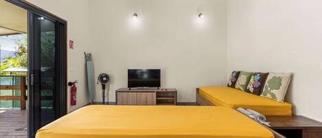 A room with two beds, a TV, a fire extinguisher, and a wooden cabinet.
