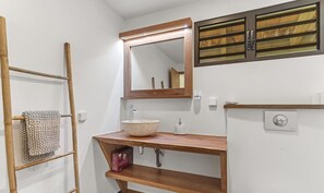 A bathroom with a wooden vanity, a large mirror, a towel rack, and a toilet paper holder.