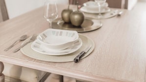 A dining table set with plates, cutlery, and glasses, with decorative apples and a wine glass on the table. - Elegance in Barranco - Cozy 2BR (Lima)