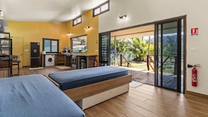 A room with two beds, a kitchen, and a sliding glass door to a balcony. - Temenino Villa Komako Seaside House (Taiarapu-Ouest)